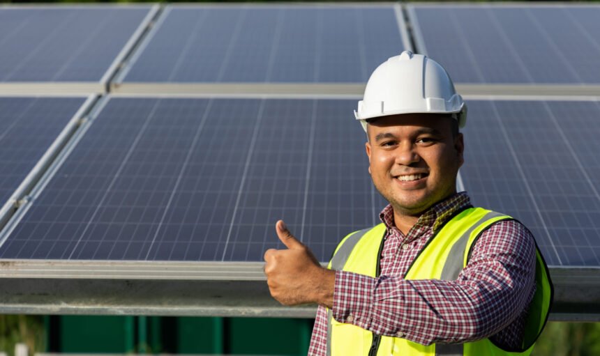 Young asian electrical engineer standing in front of Solar cell panels farm. He showing thumbs up. Solar generator power concept.